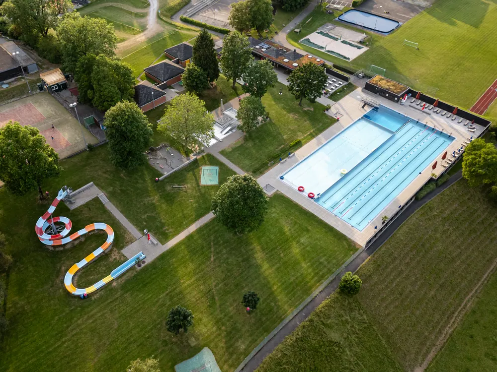 Badi Uetendorf mit Schwimmbecken, Liegewiese und Rutschbahn von oben
