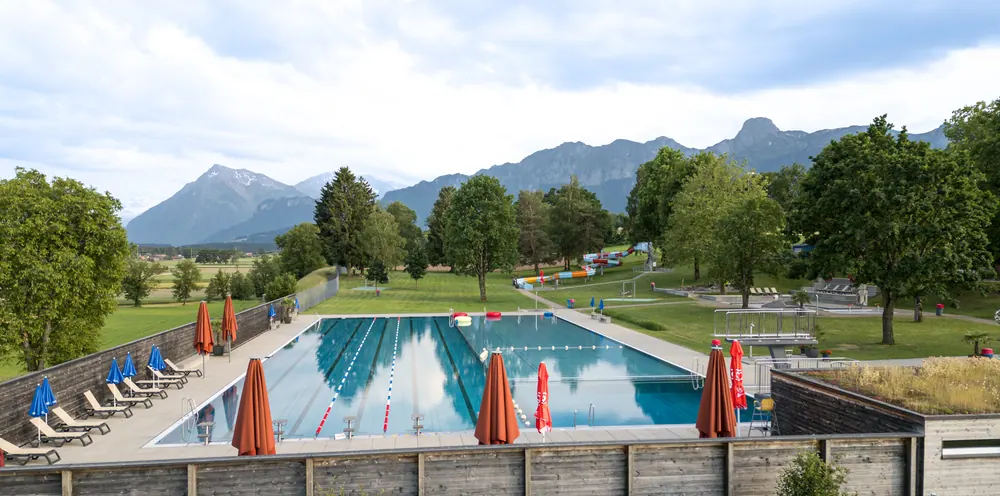 Panoramablick über das Schwimmbecken der Badi Uetendorf zu den Alpen
